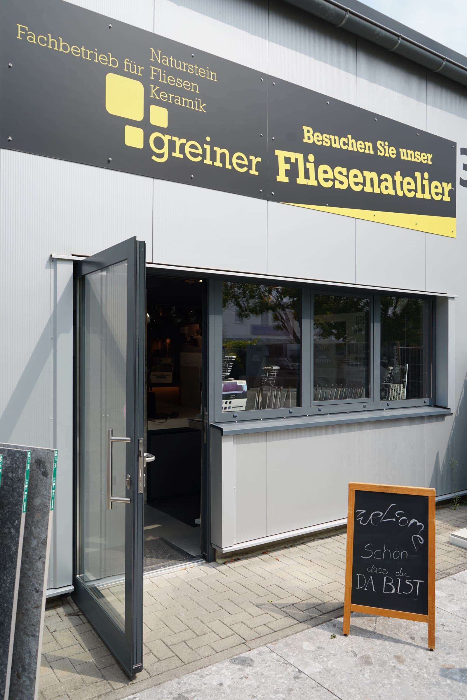 Eingang der Ausstellung Fliesenatelier Neustadt in Neustadt an der Weinstraße mit offener Tür und Welcome-Tafel